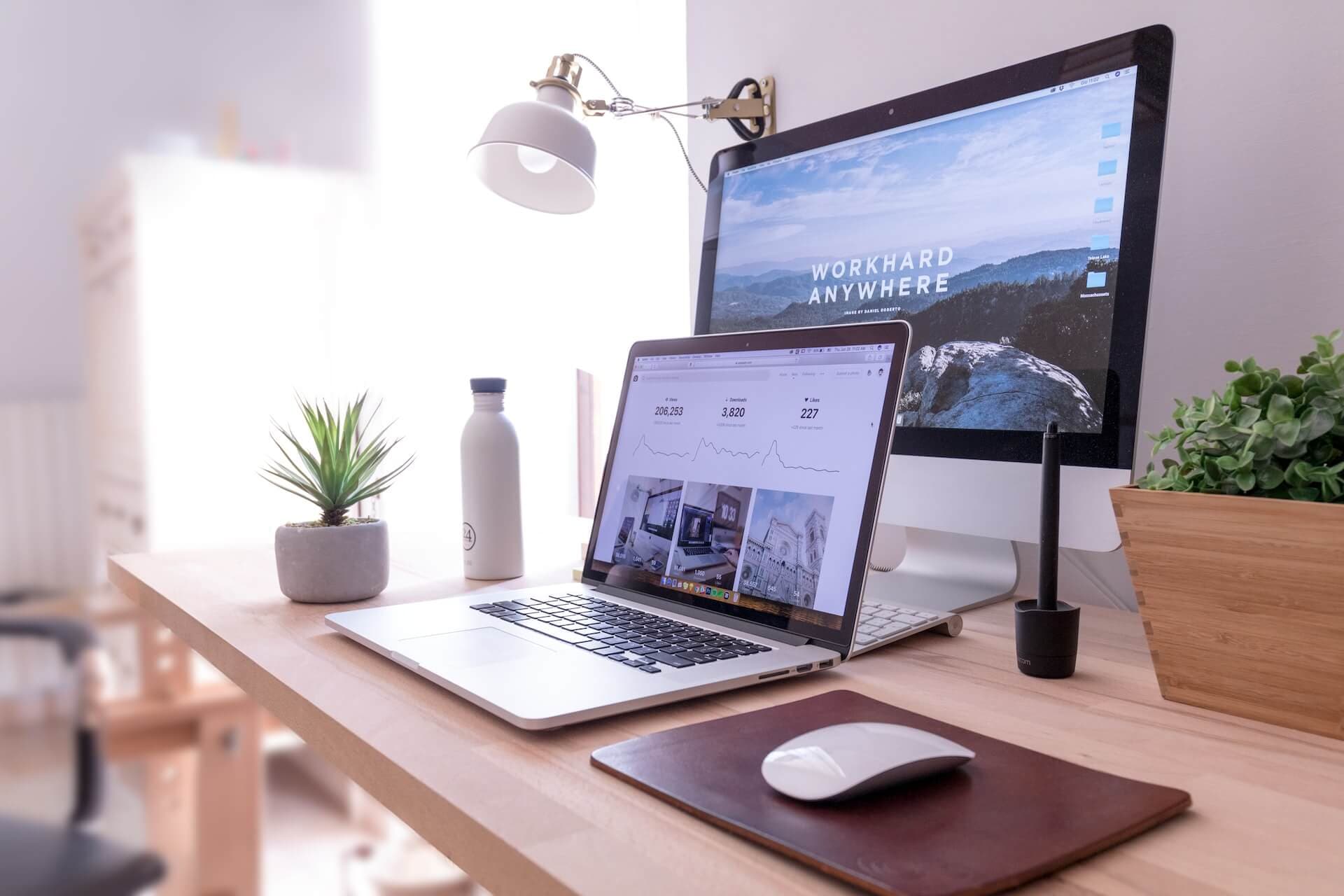 A macbook pro, magic mouse and an external monitor on a desk.